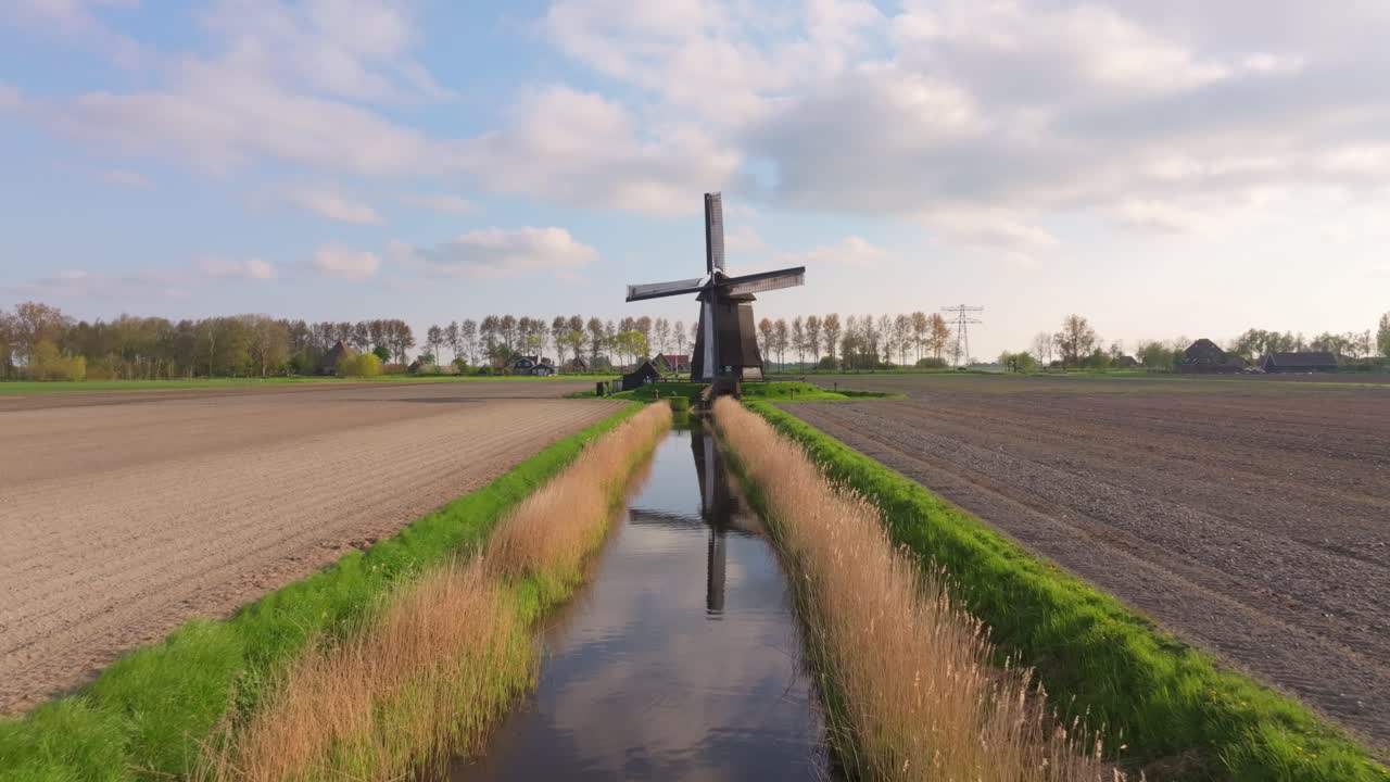 Pemandangan udara kincir angin yang berputar dengan kanal dan ladang di Belanda