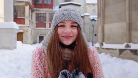 Tourist-woman-in-hat-and-gloves-blows-snow-from-palms-of-hands,-winter-Christmas-holidays-travelin