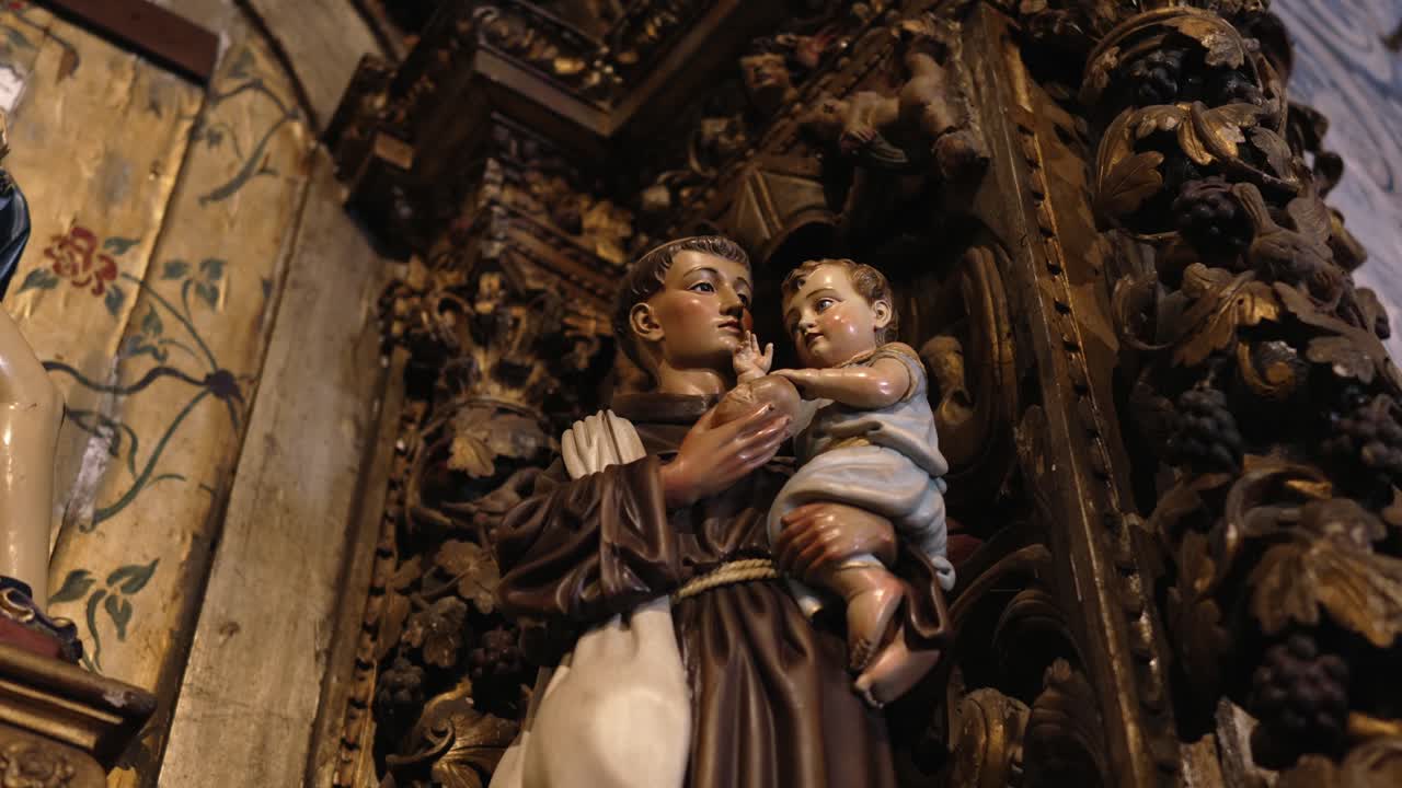 Sculpture of Saint Francis holding Baby Jesus, surrounded by intricate wooden carvings and floral details
