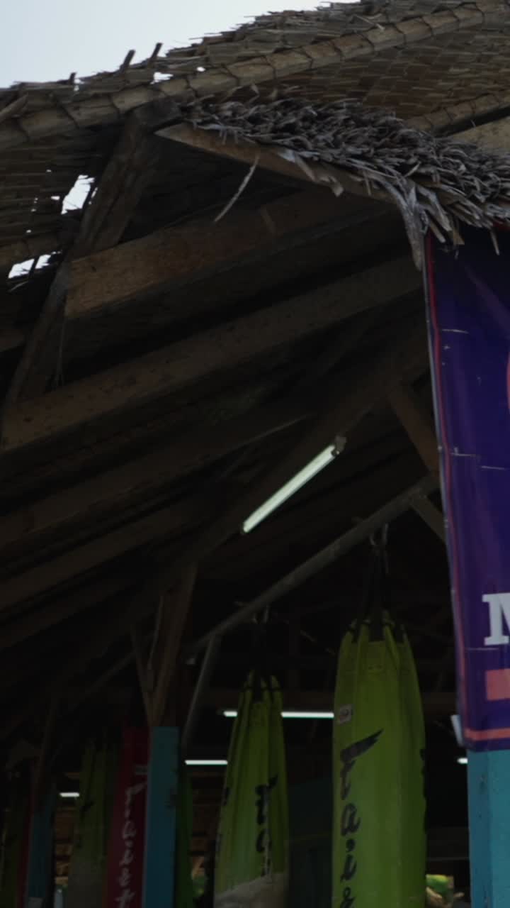 A view of a building with a thatched roof and punching bags