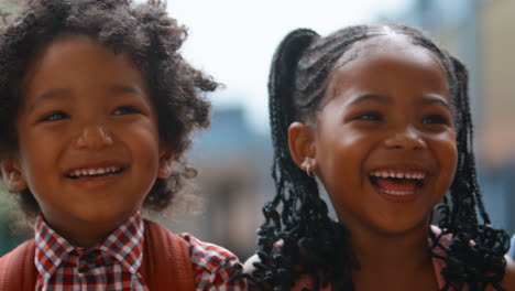 close up portrait of multi-cultural elementary school pupils sitting on wall outdoors at school