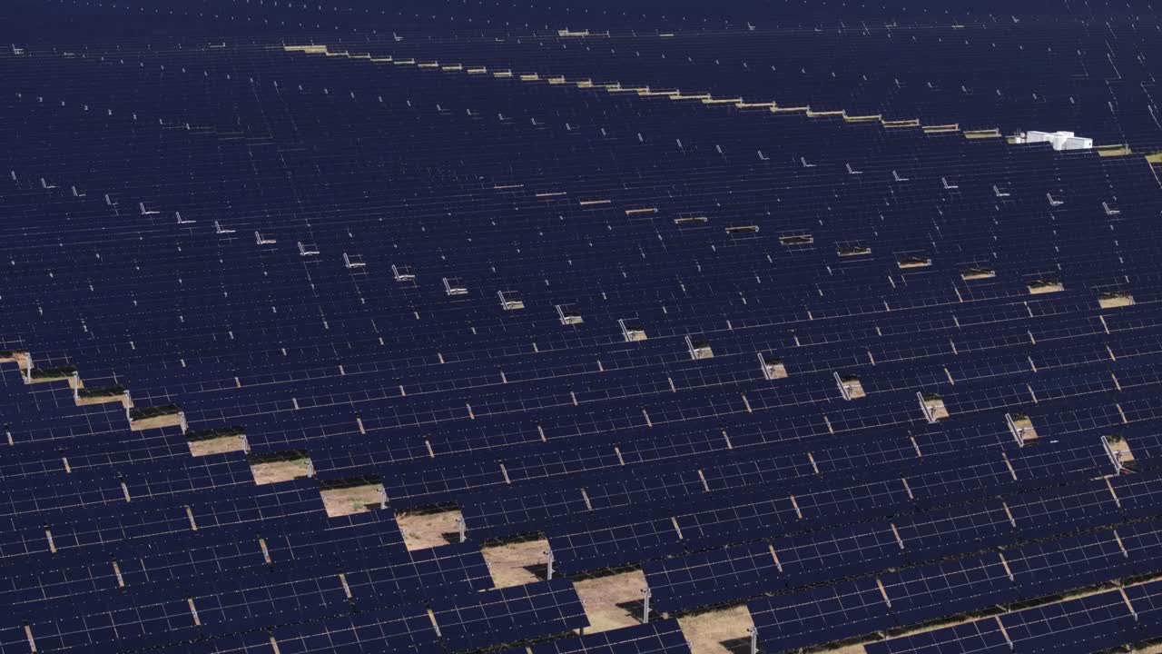 Rows of solar panels in a large field, viewed from above during the day