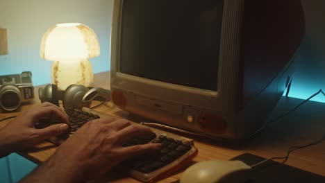 man types on keyboard and uses mouse on vintage desktop pc