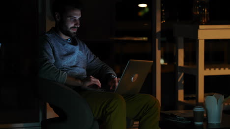 Casual-businessman-using-a-laptop-at-night-