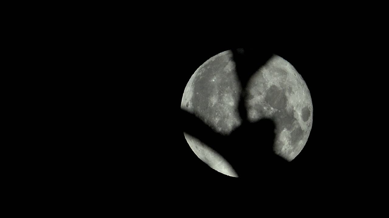 Full moon moving across the sky with leaves in foreground, in the UK