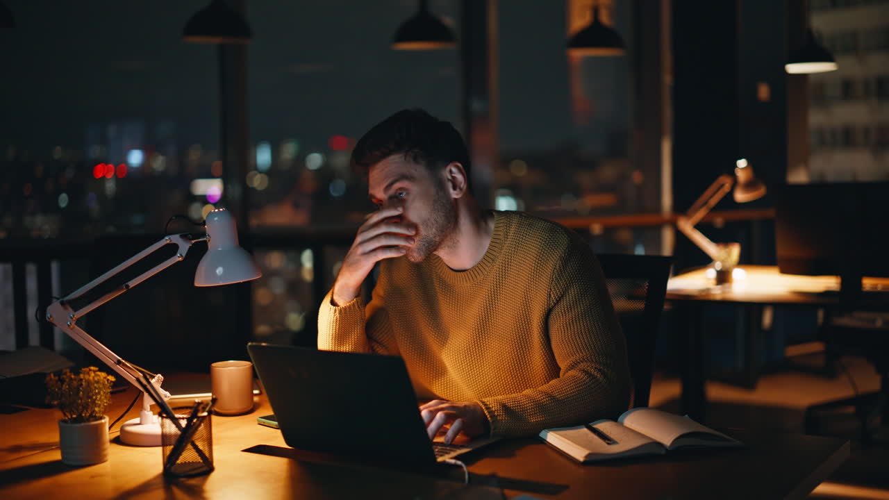 Man working on laptop at night in office