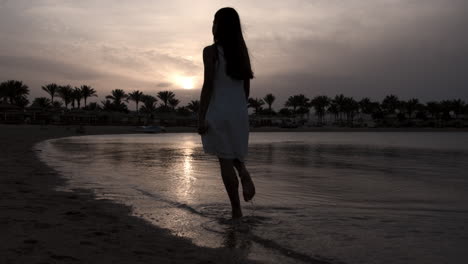 Barefoot-woman-spending-sunset-time-at-beach.-Pretty-girl-walking-at-coastline.