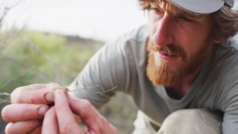 close up of bearded caucasian male survivalist examining animal dropping in wilderness
