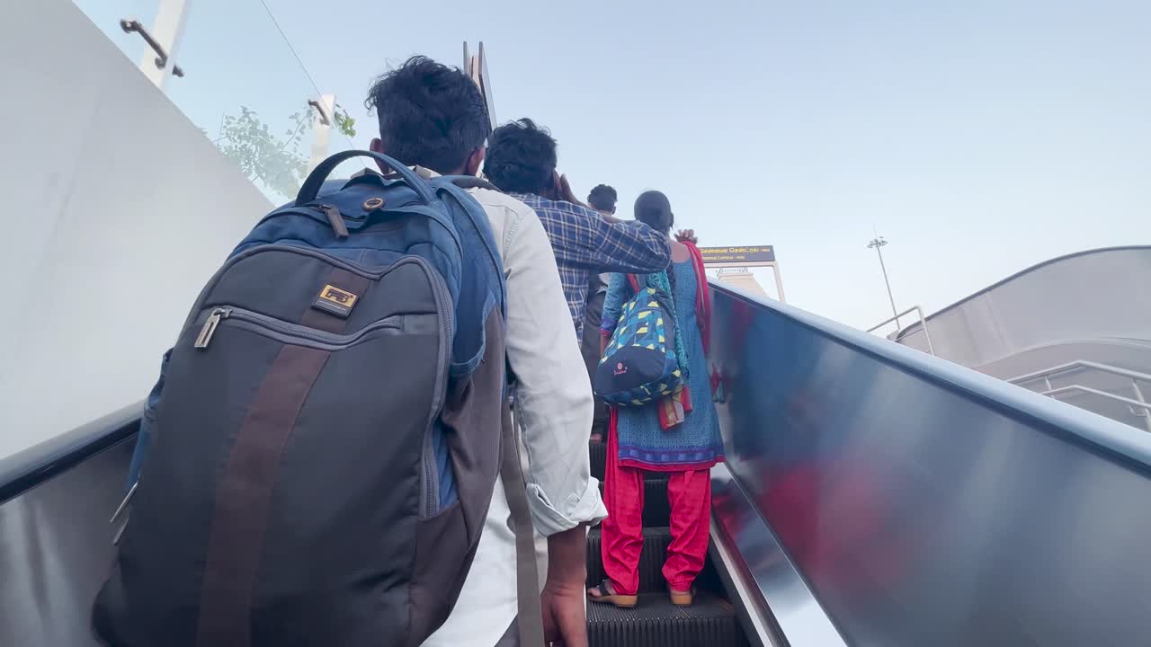 People ascending an escalator towards Chennai Central train station