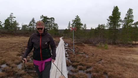 a woman and her dog walking on a mountain plank path passing to the left