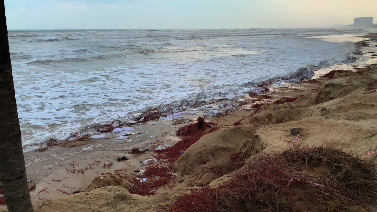 A heavily eroded beach in Da Nang, Vietnam, showing damage from strong ocean waves and coastal degradation.