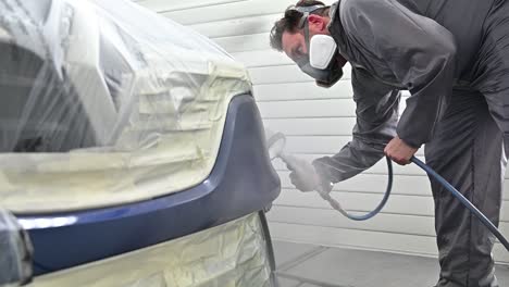 painter with protective mask spray painting vehicle, slow motion view