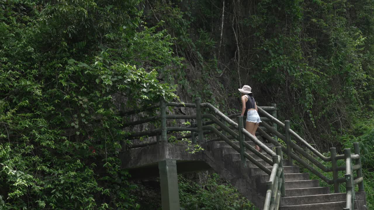 Woman climbing staircase toward Cat Ba island caves Trung Trang Vietnam nature jungle