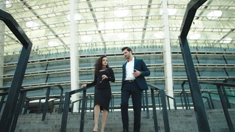 business man and woman talking together. couple walking in black suits outdoors