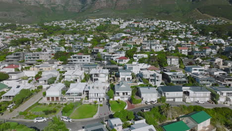 Vista-De-ángulo-Alto-De-Casas-Residenciales-O-De-Vacaciones-En-Un-Barrio-De-Lujo-Junto-Al-Mar.-Incline-Hacia-Arriba-La-Revelación-De-La-Increíble-Cordillera.-Ciudad-Del-Cabo,-Sudáfrica
