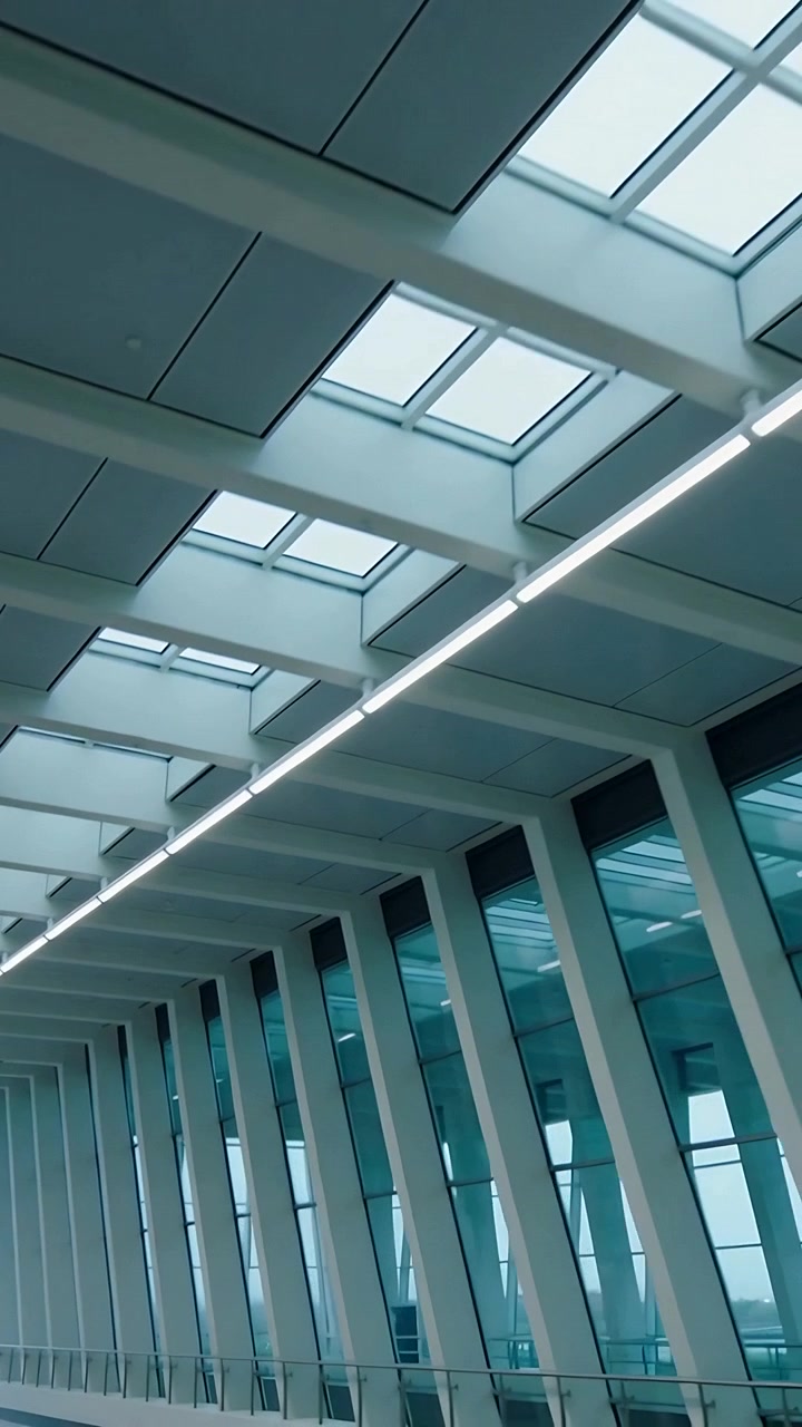 Video verticale: Telecamera che si inclina mostrando il soffitto con lucernari e LED nell'atrio, evidenziando la geometria.