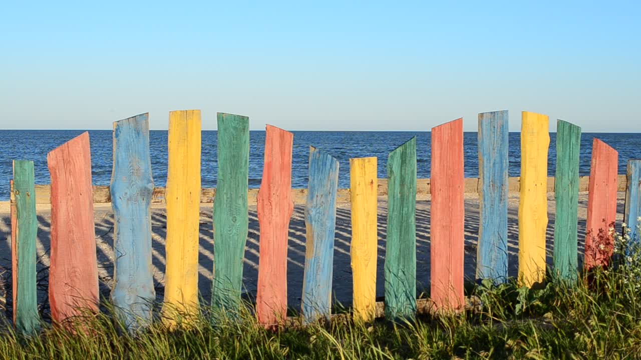 Recinzione e cielo, estate. Recinzione multicolore sulla spiaggia.