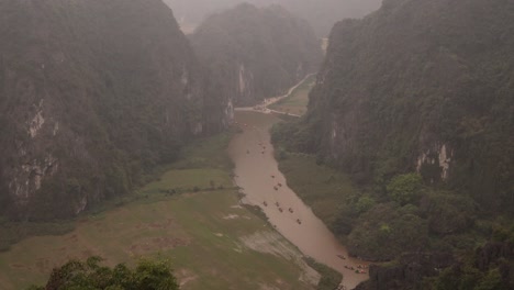 drone-shot-over-river-cutting-through-dramatic-cliffs-in-the-mountainous-region-of-Ninh-Ninh-in-Northern-Vietnam