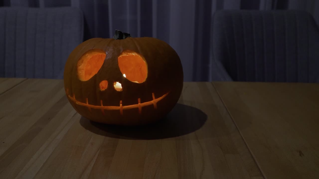 primer plano deslizante de una calabaza naranja tallada con velas encendidas dentro de casa para la decoración de halloween