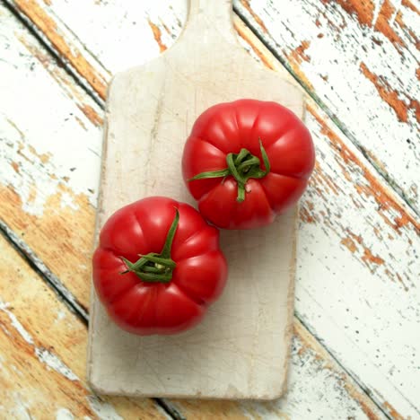 Two-fresh-eco-tomatoes-placed-on-white-wooden-cutting-board--Healthy-food-concept