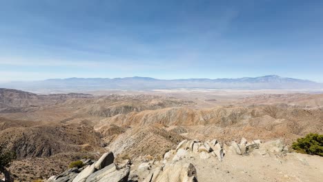 fixed shot from a rocky height shows desert terrain, hills, and mountains near palm springs in joshua tree national park