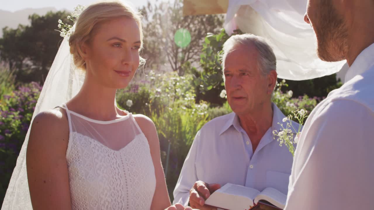 백인 신부 와 신랑 이 의식 중 결혼식 의 담당자 와 함께 야외 제단 에 서 있다