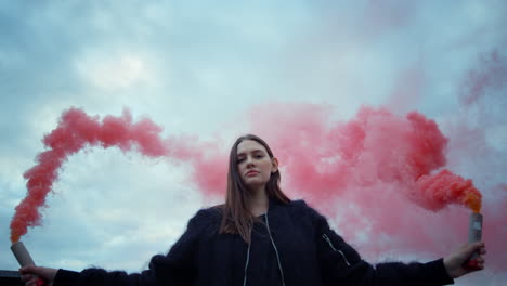 woman protesting with smoke bombs. girl posing at camera with smoke grenades