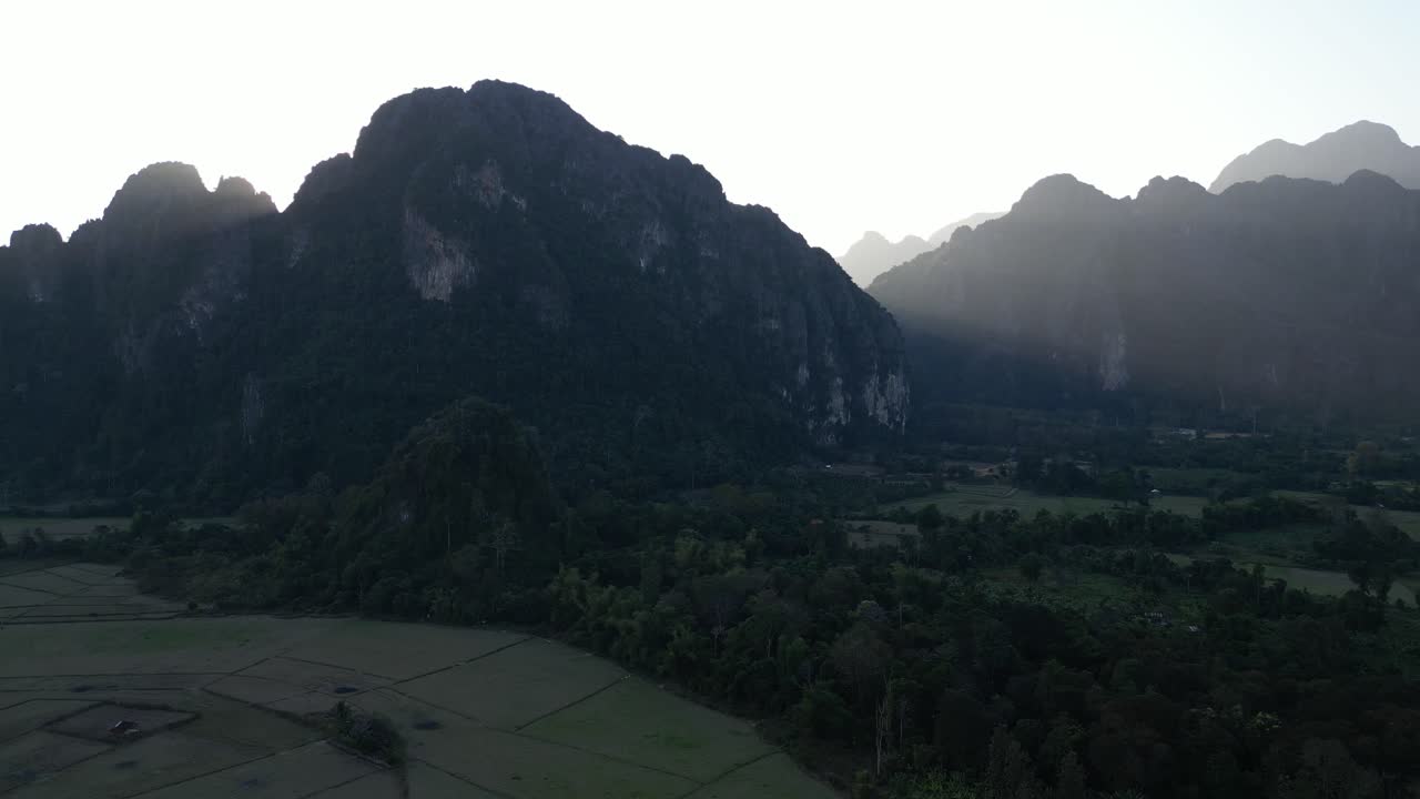 Ripresa con drone del sole che sorge dietro le montagne a Vang Vieng, la capitale dell'avventura del Laos