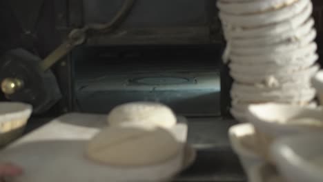 close up shot, a baker cuting and puting bread loaf in a traditional stone oven, using baker’s peel