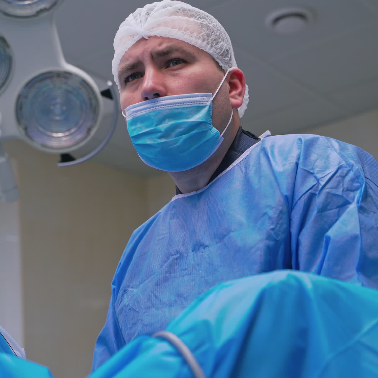 Portrait of a surgeon looking seriously. Medical specialist in a uniform and mask during the complicated surgery in modern operating room.
