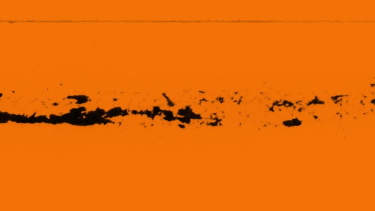Inchiostro nero astratto che si diffonde su sfondo arancione