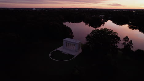 Kreisförmige-Drohnenaufnahmen-Während-Eines-Orangefarbenen-Sonnenuntergangs-Zeigen-Den-Roger-Williams-Park-Tempel-Zu-Musik