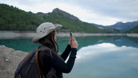mujer tomando una foto de un hermoso paisaje de lago