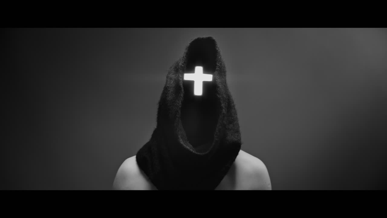 Masked and hooded man with cross of light glowing on his face rise his head