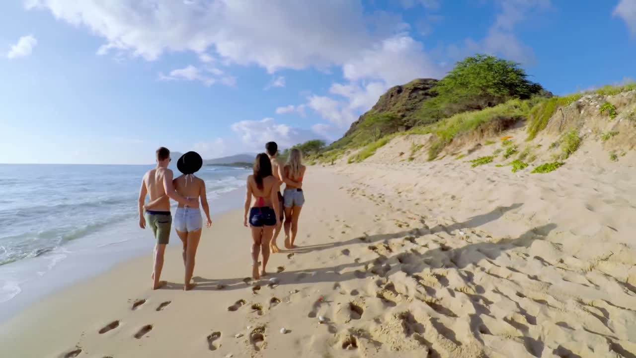 Turistas caminhando na praia 4k