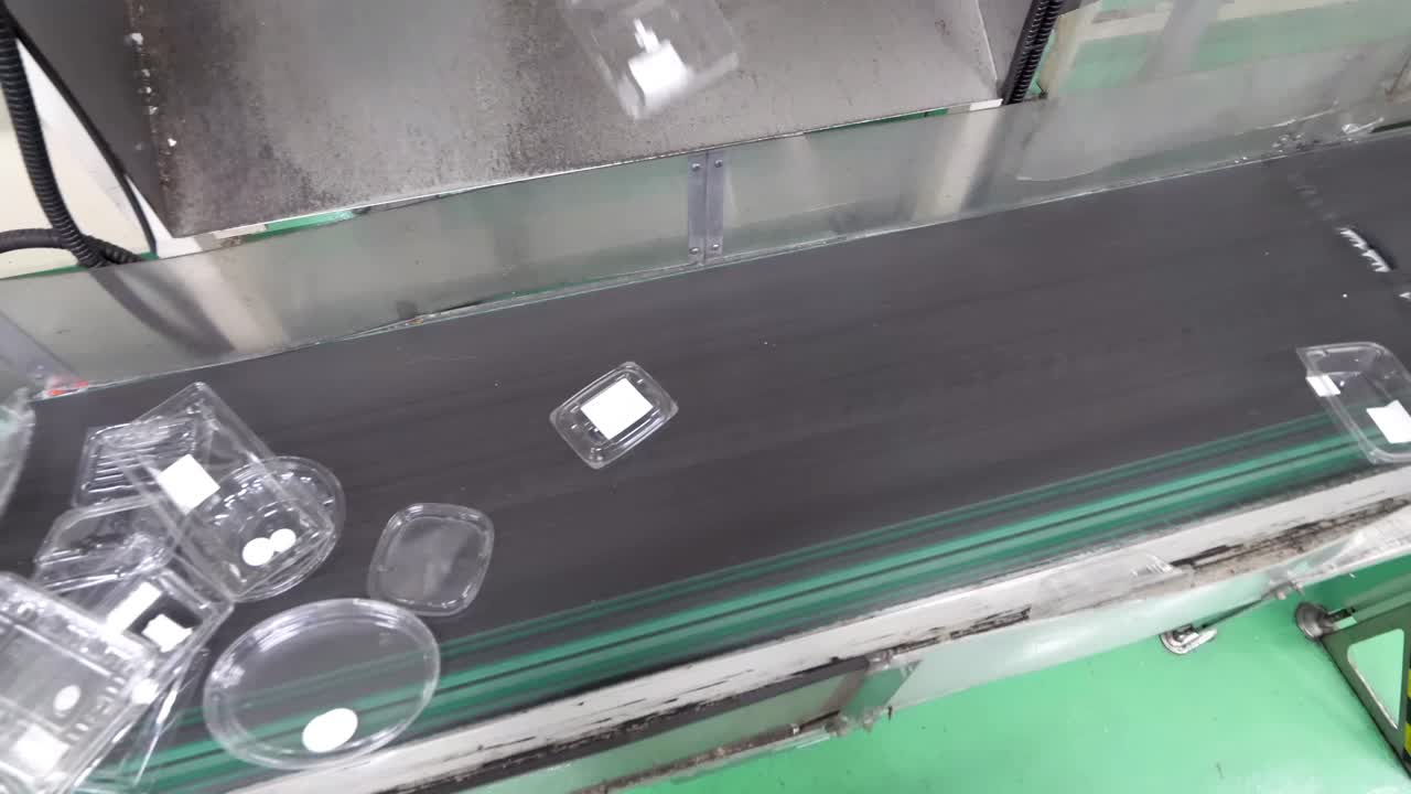 Recycling plant with a conveyor belt transporting old polypropylene boxes. Close-up view of the equipment and industrial process involved in manufacturing and production.