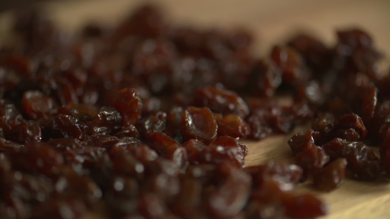 Pan across a bunch of delicious raisins on a wood cutting board