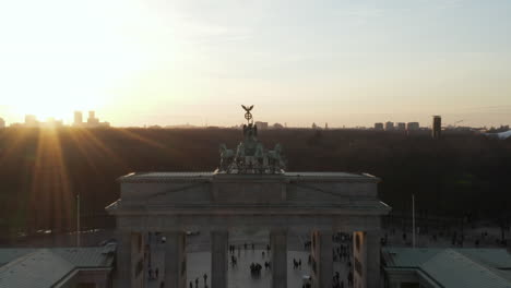 Antena:-Acercándose-Lentamente-A-La-Puerta-De-Brandenburgo-Y-Al-Tiergarten-Bajo-La-Hermosa-Luz-Del-Sol-Del-Atardecer-Con-Una-Vista-Cercana-De-La-Estatua-Verde-Quadriga-En-Berlín,-Alemania