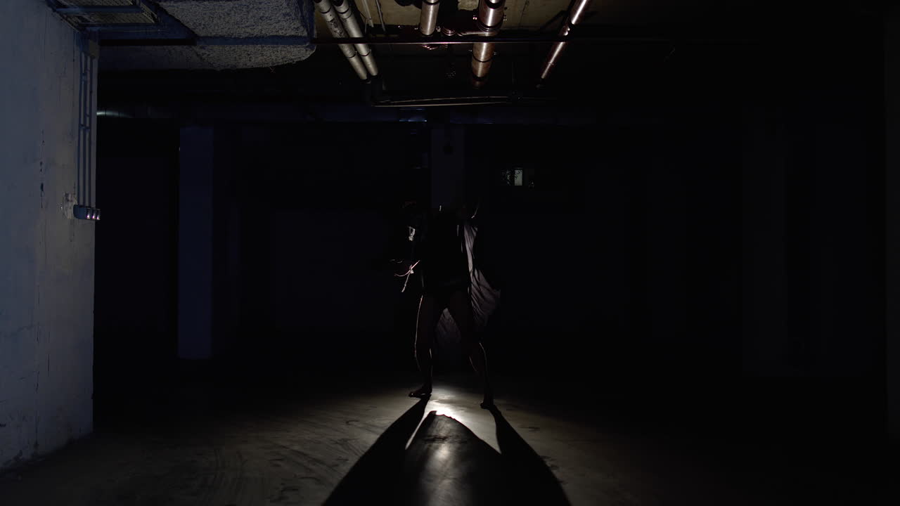 hombre aterrador en esqueleto maquillaje de halloween en el pasillo de estacionamiento oscuro por la noche va en cámara lenta