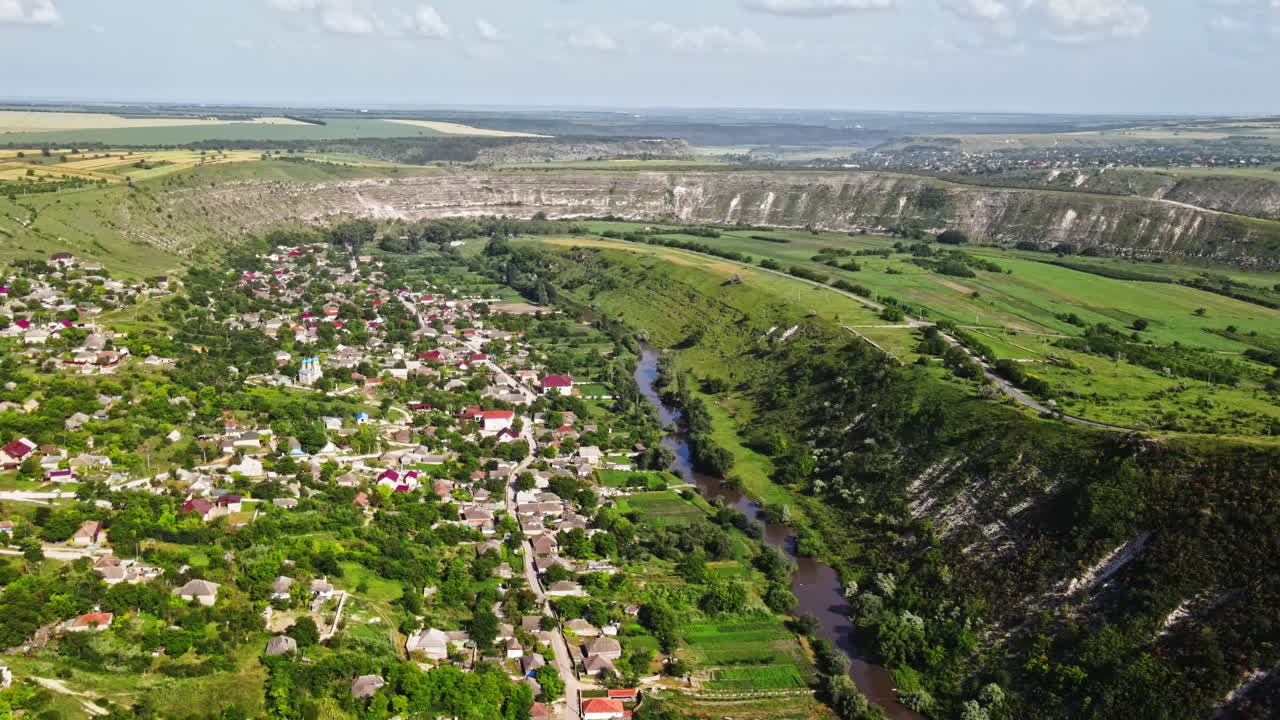 Aerial drone view of nature, valley with river and village, hills and fields, greenery, Moldova