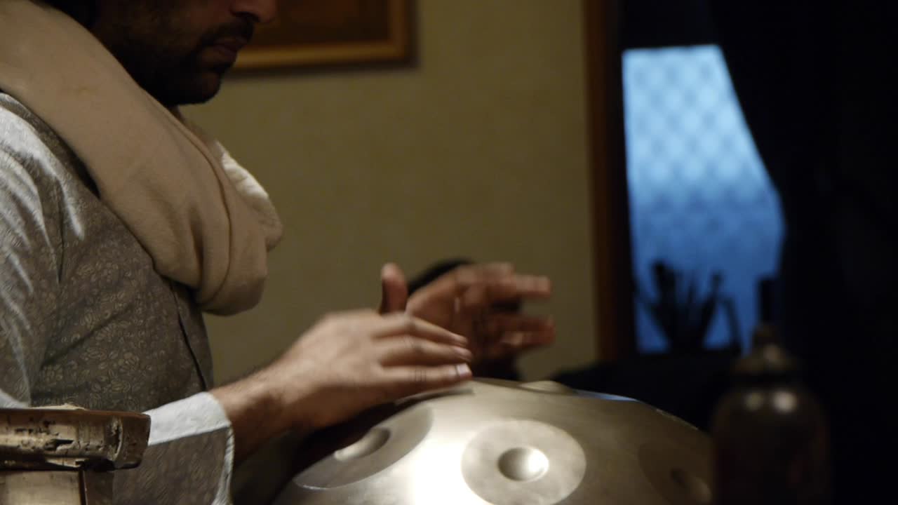 Indian handpan player drumming musical notes on his instrument