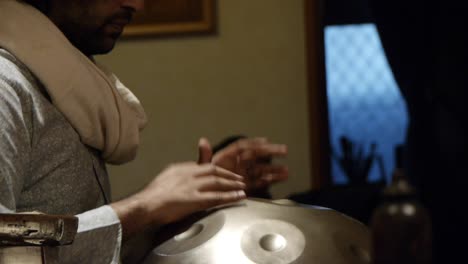 indian handpan player drumming musical notes on his instrument