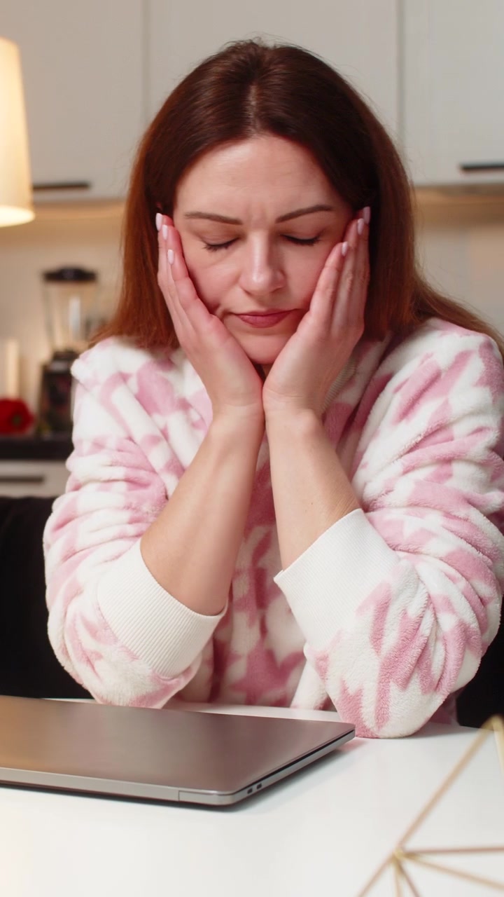 Donna adulta irritata dal carico di lavoro agita la mano, chiude il portatile, termina il turno tardivo e pianifica un nuovo inizio per domani.