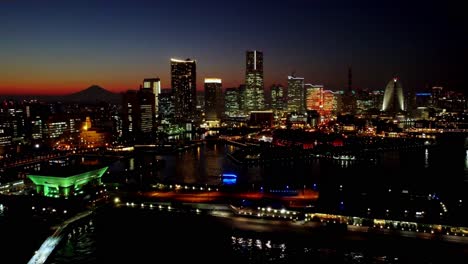 Horizonte-Al-Atardecer-De-Una-Ciudad-Bulliciosa-Con-Luces-Reflejadas-En-El-Agua,-Mt