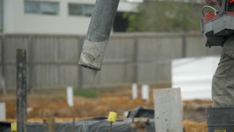 close up cement pump hose pours out concrete onto property slab