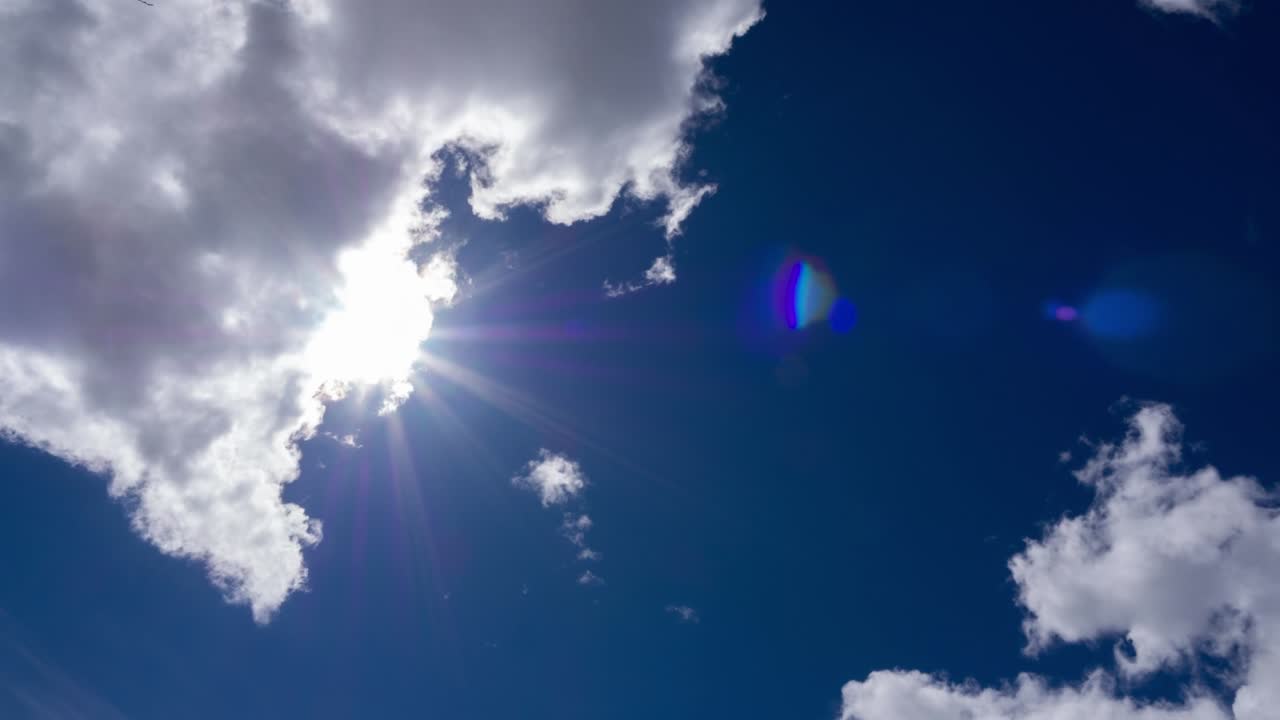 4k b-roll TimeLapse bright sunlight ray flare n sunbeam shining through white cumulus cloud on Beautiful sunny dark blue sky in tropical summer sunlight n sunray at daylight sunshine day.