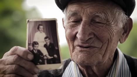 an intimate moment of reminiscence: an elderly man holding a cherished photograph of his youth, capturing a bittersweet connection to the past and fond memories with loved ones