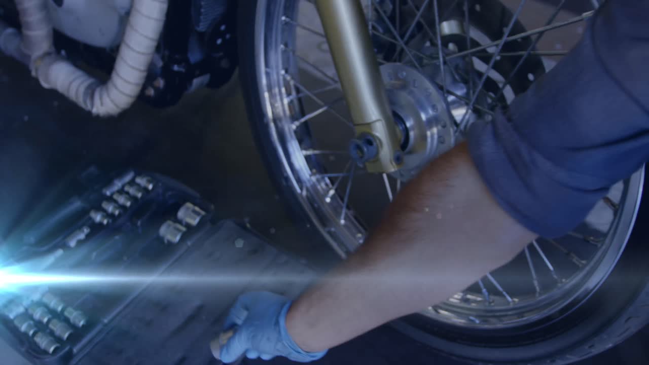 animación de luces brillantes sobre un mecánico caucásico reparando una motocicleta en un garaje