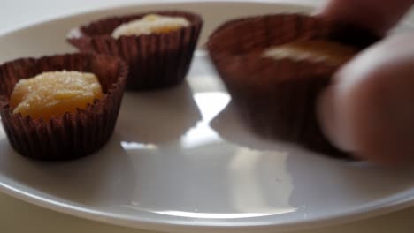 sweet treats on a white plate, yemas de santa teresa in paper cups, soft light