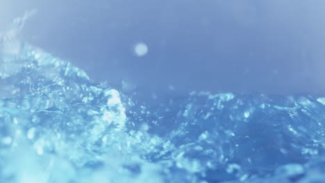 スローモーションのきれいな水面が画面を水しぶきで満たします。水滴と波打つ液体表面に気泡が入ります。